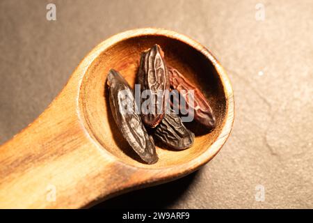 Haricots Tonka dans une cuillère en bois sur un fond sombre. Banque D'Images