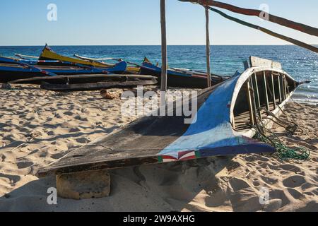 Bateaux de pêche en bois simples sur une plage de sable près du petit village de Madagascar, mer calme en arrière-plan. Banque D'Images