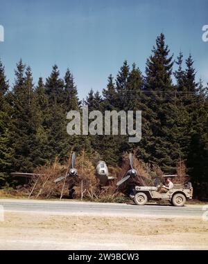 Un chasseur bombardier allemand camouflé stationné le long de l'Autobahn (super autoroute près de Munich) est inspecté par un GI dans une jeep. En raison des bombardements intensifs des aérodromes, les Allemands utilisèrent l'Autobahn comme piste 1945 Banque D'Images