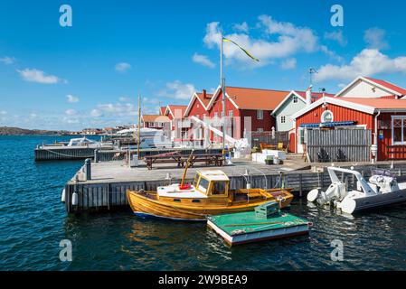 Entrepôts aux façades typiques en bois rouge et bateaux de pêche dans le port de Skärhamn dans l'archipel de l'île de Tjörn en été, Suède Banque D'Images