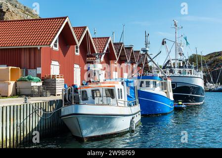 Entrepôts aux façades typiques en bois rouge et bateaux de pêche dans le port de Skärhamn dans l'archipel de l'île de Tjörn en été, Suède Banque D'Images