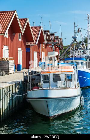 Entrepôts aux façades typiques en bois rouge et bateaux de pêche dans le port de Skärhamn dans l'archipel de l'île de Tjörn en été, Suède Banque D'Images