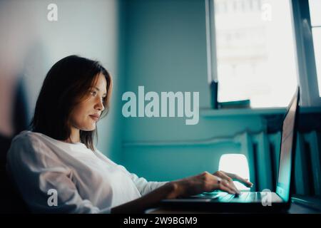 Une jeune jolie fille dans la dépression travaille à la maison, tient une vidéoconférence, regarde des films Banque D'Images