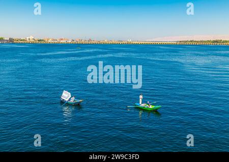 Les vendeurs de textiles sur leurs bateaux approchent un bateau de croisière en attendant d'entrer dans l'écluse d'Esna. Les vendeurs espèrent vendre des marchandises aux touristes. Esna, Égypte – octobre 20 Banque D'Images