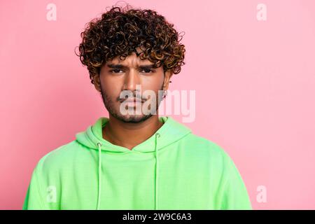 Portrait de drôle grimace bouleversé jeune gars indien portant vert élégant sweat à capuche perdu sa motivation isolé sur fond de couleur rose Banque D'Images