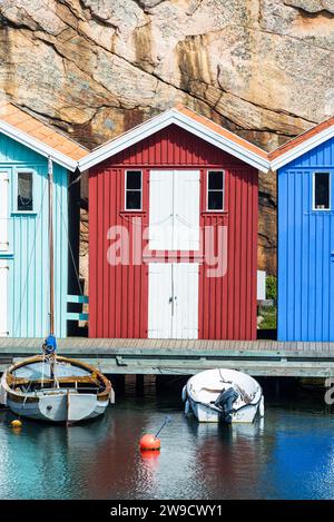 Entrepôt avec façade en bois rouge devant des rochers de granit sur la promenade du port de Smögen dans l'archipel de la côte ouest suédoise Banque D'Images