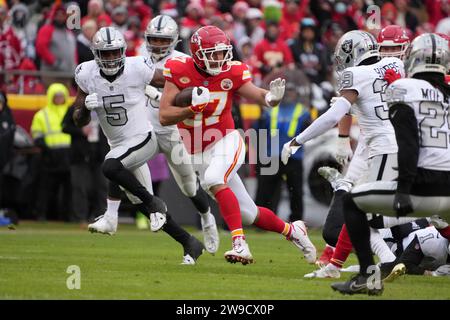 Kansas City Chiefs Tight End Travis Kelce (87) porte le ballon contre le linebacker Divine Deablo (5) des Raiders de Las Vegas lors d'un match de football de la NFL, lundi 25 décembre 2023, à Kansas City, Mo. Les Raiders ont battu les Chiefs 20-14. Banque D'Images