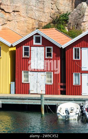 Entrepôt avec façade en bois rouge devant des rochers de granit sur la promenade du port de Smögen dans l'archipel de la côte ouest suédoise Banque D'Images