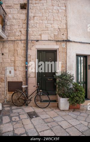 Vélo garé près de la porte verte de la vieille maison en pierre dans Polignano a Mare vieille ville Banque D'Images