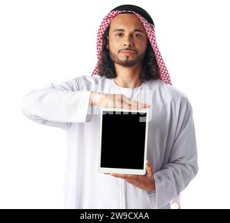 Jeune homme arabe dans la robe traditionnelle thobe montrant tablette numérique avec écran noir sur fond blanc Banque D'Images