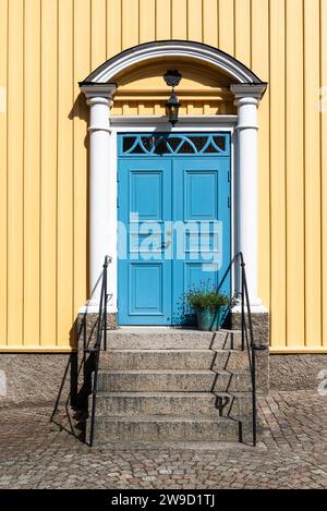 Portail d'entrée avec porte bleue sur une maison en bois jaune dans le centre de Fjällbacka sur la côte ouest suédoise au soleil Banque D'Images