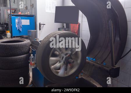 Équilibrage de roue d'ordinateur sur la machine-outil d'équipement spécial dans le service de réparation automobile. Support pour l'équilibrage des roues de voiture. La roue est floue en raison du Banque D'Images