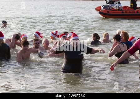 RNLI Boxing Day DIP en 2023. Les gens bravent le froid et la mer pour collecter des fonds pour les bateaux de sauvetage West Mersea. Banque D'Images