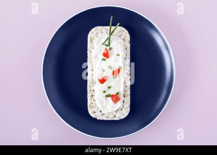 Gâteau de riz garni de fromage à pâte molle, tomates et ciboulette Banque D'Images