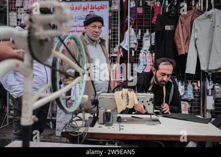 Un tailleur palestinien nommé Abu Adam Dolah utilise une machine à coudre pédalée qu’il a développée en raison d’une pénurie d’électricité Un tailleur palestinien nommé Abu Adam Dolah utilise une machine à coudre pédalée qu’il a développée en raison d’une pénurie d’électricité alors qu’Israël continue de bloquer l’électricité à Rafah, Gaza, le 27 décembre 2023. Gashda a attaché des pédales de vélo à sa machine à coudre d'une manière qui lui permet d'utiliser la machine sans électricité. Photo de Bashar Taleb apaimages Rafah bande de Gaza territoire palestinien 271223 Rafah BT 0010 Copyright : xapaimagesxBasharxTalebxapaimagesx Banque D'Images