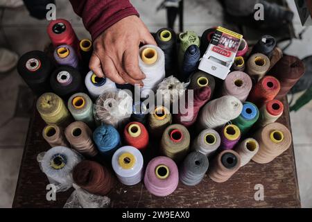 Un tailleur palestinien nommé Abu Adam Dolah utilise une machine à coudre pédalée qu’il a développée en raison d’une pénurie d’électricité Un tailleur palestinien nommé Abu Adam Dolah utilise une machine à coudre pédalée qu’il a développée en raison d’une pénurie d’électricité alors qu’Israël continue de bloquer l’électricité à Rafah, Gaza, le 27 décembre 2023. Gashda a attaché des pédales de vélo à sa machine à coudre d'une manière qui lui permet d'utiliser la machine sans électricité. Photo de Bashar Taleb apaimages Rafah bande de Gaza territoire palestinien 271223 Rafah BT 0015 Copyright : xapaimagesxBasharxTalebxapaimagesx Banque D'Images