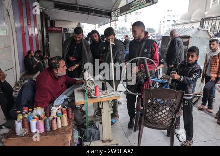 Un tailleur palestinien nommé Abu Adam Dolah utilise une machine à coudre pédalée qu’il a développée en raison d’une pénurie d’électricité Un tailleur palestinien nommé Abu Adam Dolah utilise une machine à coudre pédalée qu’il a développée en raison d’une pénurie d’électricité alors qu’Israël continue de bloquer l’électricité à Rafah, Gaza, le 27 décembre 2023. Gashda a attaché des pédales de vélo à sa machine à coudre d'une manière qui lui permet d'utiliser la machine sans électricité. Photo de Bashar Taleb apaimages Rafah bande de Gaza territoire palestinien 271223 Rafah BT 0011 Copyright : xapaimagesxBasharxTalebxapaimagesx Banque D'Images