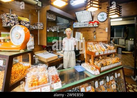 Tokyo, Japon 1 octobre 2023 : Femme au comptoir d'une pâtisserie de riz croustillante à Yanaka au Japon. Banque D'Images