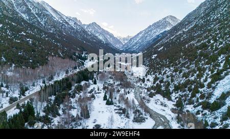 Vue aérienne des montagnes enneigées et des sapins dans le parc naturel Ala-Archa au Kirghizistan en hiver Banque D'Images