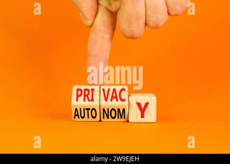 Symbole de confidentialité ou d'autonomie. Mot concept vie privée ou autonomie sur cubes en bois. Belle table orange fond orange. Main d'homme d'affaires. pri entreprise Banque D'Images