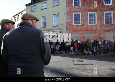 Deux hommes en vêtements de campagne traditionnels regardent les partisans de la chasse alors qu'ils s'alignent le long des rues de la ville de marché pour accueillir la chasse. Action contre la cruauté envers les animaux, une manifestation a eu lieu dans le centre-ville de Bungay alors que les Harriers de Waveney et Norfolk défilent dans les rues pour soutenir la campagne. Les manifestants ont déclaré que, bien qu'il s'agisse d'une interdiction de la chasse traditionnelle au renard, les animaux sont toujours tués pendant l'alternative de la chasse au sentier et ils appellent à une interdiction totale. Banque D'Images