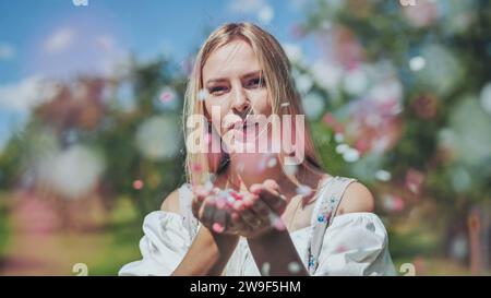 Une fille souffle des confettis en papier multicolores de ses mains. Banque D'Images