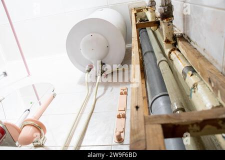 Chauffe-eau et tuyaux dans un appartement résidentiel après avoir remplacé le tuyau par un nouveau, salle de bains et réparations de plomberie Banque D'Images