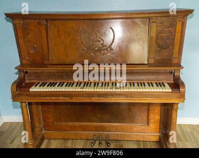 Vieux piano à queue droit en bois touches noires et blanches avec applique détaillée sur instrument de la fin des années 1800, usé, cassé, endommagé et bien joué. FRO Banque D'Images