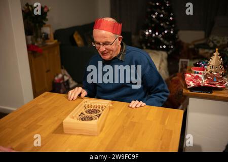 Grands-parents jouant au jeu de flipper en bois sur table le jour de Noël, Angleterre, Royaume-Uni Banque D'Images