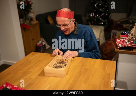 Grands-parents jouant au jeu de flipper en bois sur table le jour de Noël, Angleterre, Royaume-Uni Banque D'Images