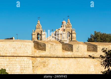 Les deux clochers baroques et le dôme de la cathédrale Saint-Paul s’élèvent au-dessus des remparts de Mdina. L’architecte Lorenzo Gafà a construit la cathédrale entre 1696 et 1705 pour remplacer son prédécesseur médiéval, détruit lors du tremblement de terre de 1693. Cette vue sur les remparts de la ville faisait partie des lieux utilisés à Mdina pour la première saison de Game of Thrones en 2011. Banque D'Images