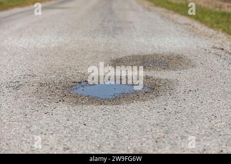 Gros plan de la cagoule, trou de chuckhole, sur la chaussée asphaltée. Concept de réparation, d'entretien et de dommages de rue. Banque D'Images