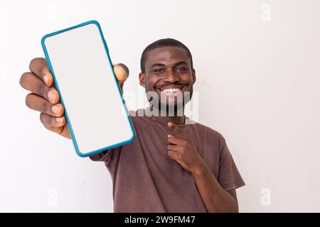 Recommandation. Portrait d'un homme afro-américain noir excité tenant un grand smartphone avec un écran blanc à la main, montrant près de la caméra et poi Banque D'Images