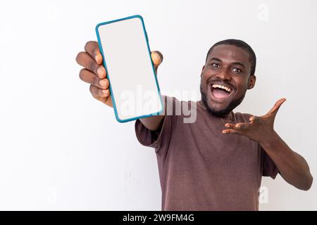 ,Portrait de gars afro-américain excité tenant grand smartphone avec écran blanc blanc en main, montrant près de la caméra et pointant vers le ph Banque D'Images