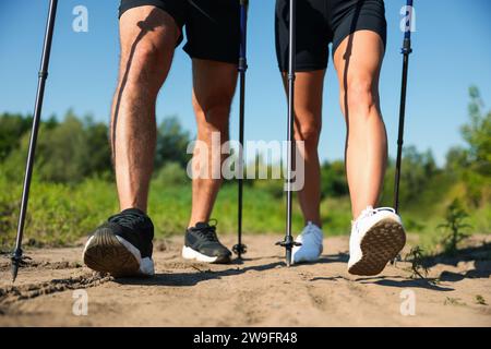 Couple pratiquant la marche nordique avec des bâtons à l'extérieur sur une journée ensoleillée, closeup Banque D'Images