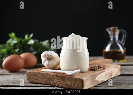 Sauce mayonnaise fraîche dans un bocal en verre et ingrédients sur une table en bois Banque D'Images