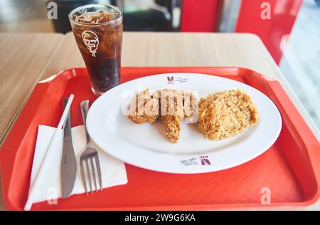 Danang, Vietnam - 06.27.2023 : déjeuner dans un café fast-food. Ailes de KFC sur une assiette de Coca-Cola Banque D'Images