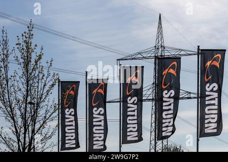 Koblenz, Allemagne - 22 avril 2021 : drapeaux avec le logo et le lettrage du détaillant Saturn devant un pylône haute tension Banque D'Images