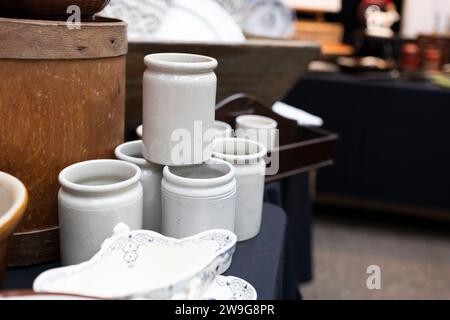 Bocaux en céramique blanche pour produits en vrac sur une vieille commode brune sur un marché d'antiquités. Banque D'Images