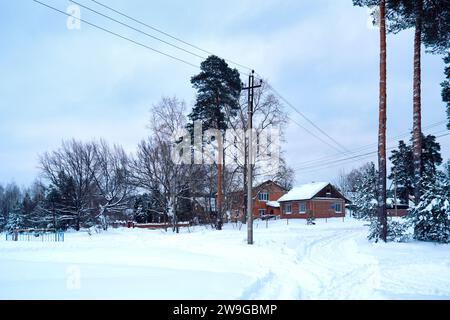 Ryazan, Russie - 16 décembre 2023 : paysage rural d'hiver avec des maisons, des arbres et des pins dans la neige Banque D'Images