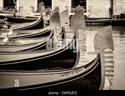 Vue vintage noir et blanc des arcs en métal des gondoles vénitiennes traditionnelles ancrées dans un canal dans le quartier de San Marco, Venise, Italie Banque D'Images