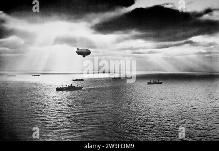 Sunset over the Atlantic trouve un convoi des États-Unis se déplaçant pacifiquement vers sa destination pendant la Seconde Guerre mondiale Un blimp de l'US Navy, planant au-dessus, est à l'affût de tout signe de sous-marins ennemis, en juin 1943. Banque D'Images