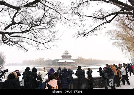 (231228) -- PÉKIN, 28 déc. 2023 (Xinhua) -- les visiteurs prennent des photos devant une tourelle du musée du palais dans les chutes de neige à Beijing, capitale de la Chine, le 13 décembre 2023. Créé sous la dynastie Yuan (1271-1368), l'axe central de Pékin, ou Zhongzhouxian, s'étend sur 7,8 kilomètres entre la porte de Yongding au sud de la ville et la Tour du tambour et du clocher au nord. La plupart des grands bâtiments de la vieille ville de Pékin se trouvent le long de cet axe. Portes, palais, temples, places et jardins de la vieille ville sont tous reliés à l'axe. Comme ils ont été témoins des activités folkloriques le long de la ligne f Banque D'Images
