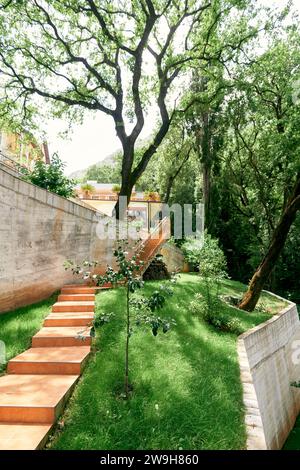 Escalier carrelé dans un jardin verdoyant le long d'une clôture en pierre Banque D'Images