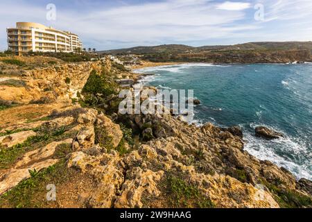 Le Radisson Blu Resort & Spa Malta Golden Sands s'élève au-dessus des falaises près de Manikata, à Malte, surplombant Golden Bay. Un étroit sentier côtier serpente à travers des roches encroûtées et couvertes d'herbes sur la pente en dessous de l'hôtel. Banque D'Images