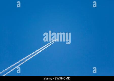 La pollution de l'air par les avions s'oppose pendant les déplacements en hauteur dans un ciel bleu clair Banque D'Images