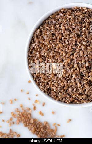 Gros plan des grains de blé dans le bol sur fond de marbre. Concept de nourriture saine. Banque D'Images