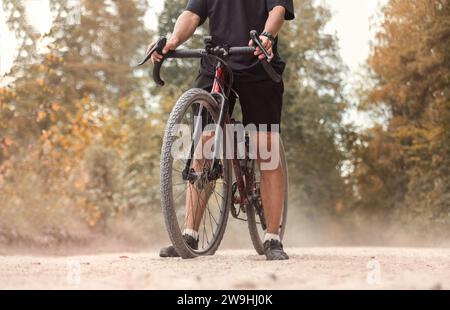 Cycliste avec un vélo de gravier sur une route de campagne poussiéreuse. Concept de style de vie actif. Banque D'Images