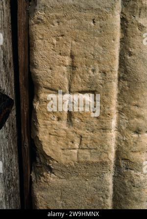 Une « Croix de Malte » (en fait une pattée de croix) sculptée sur le montant de porte E de la porte intérieure S de l'église St Andrew, Hartburn, Northumberland, Angleterre. Banque D'Images