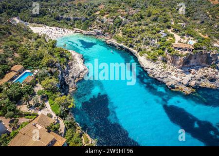 Vue aérienne sur les rives isolées de Cala Llombards, où les eaux cristallines et le sable doré créent un havre de paix sur la côte de Majorque. Banque D'Images